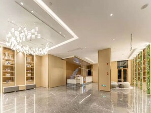 A modern hotel lobby with a marble floor, a reception desk, and a unique ceiling light fixture. - Lavande Hotel (Xiamen)