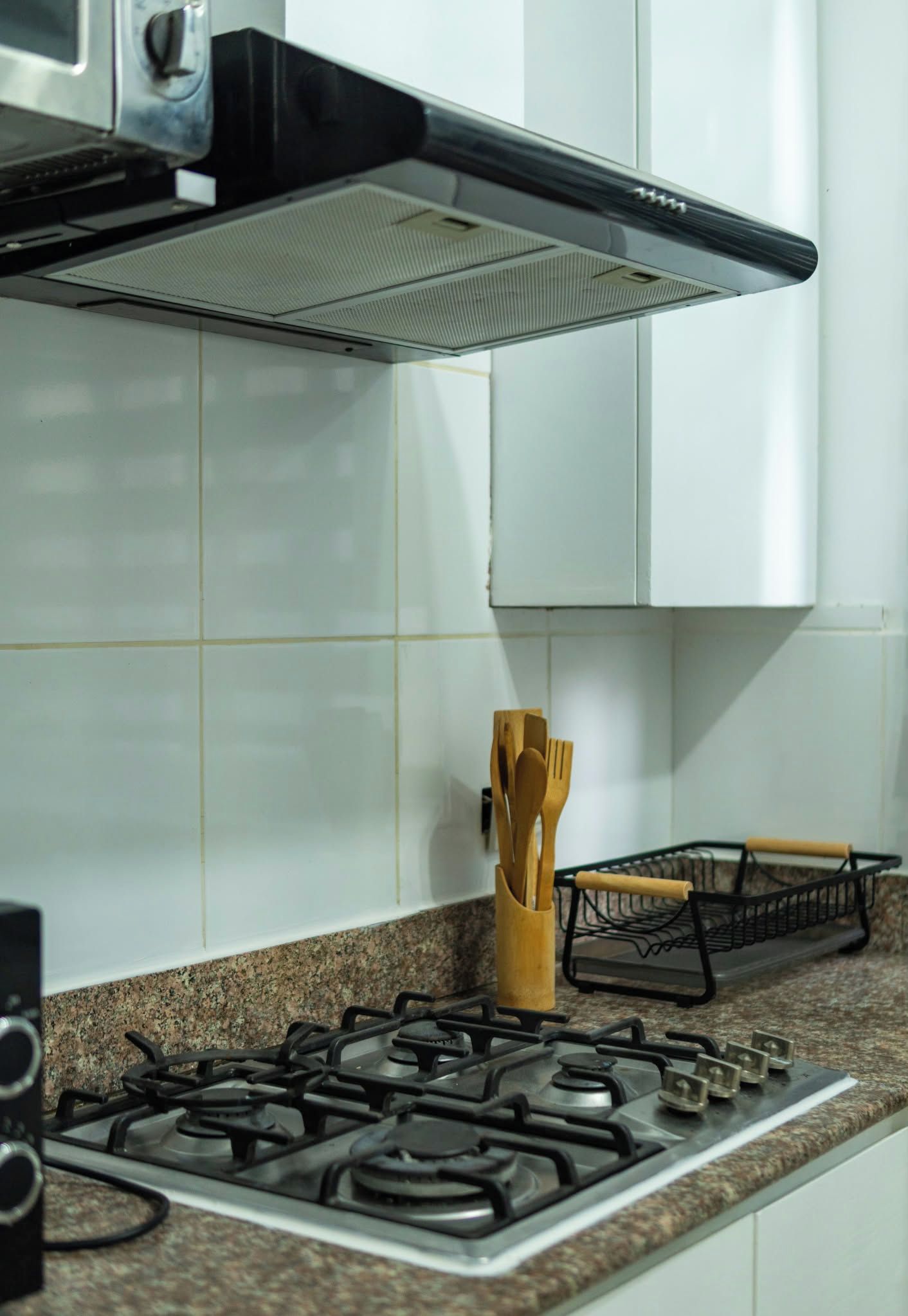 Una cucina con piano cottura a gas, cappa aspirante e ripiano per spezie.
