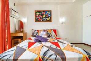 Ein Hotelzimmer mit einem Bett, einem Schreibtisch, einem Spiegel und einem Gemälde an der Wand.