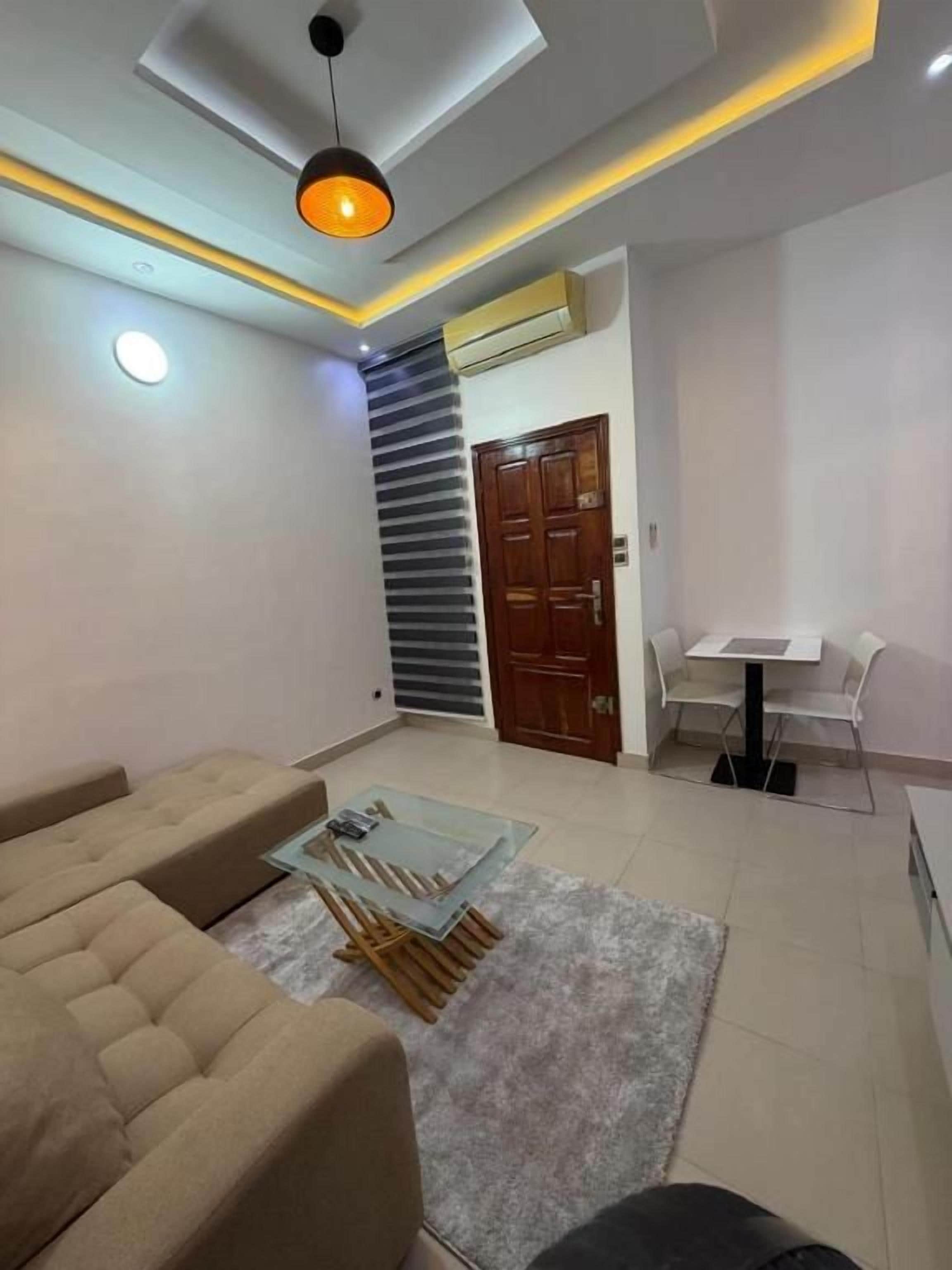 A modern living room with a sofa, a glass coffee table, and a dining area with a table and chairs.