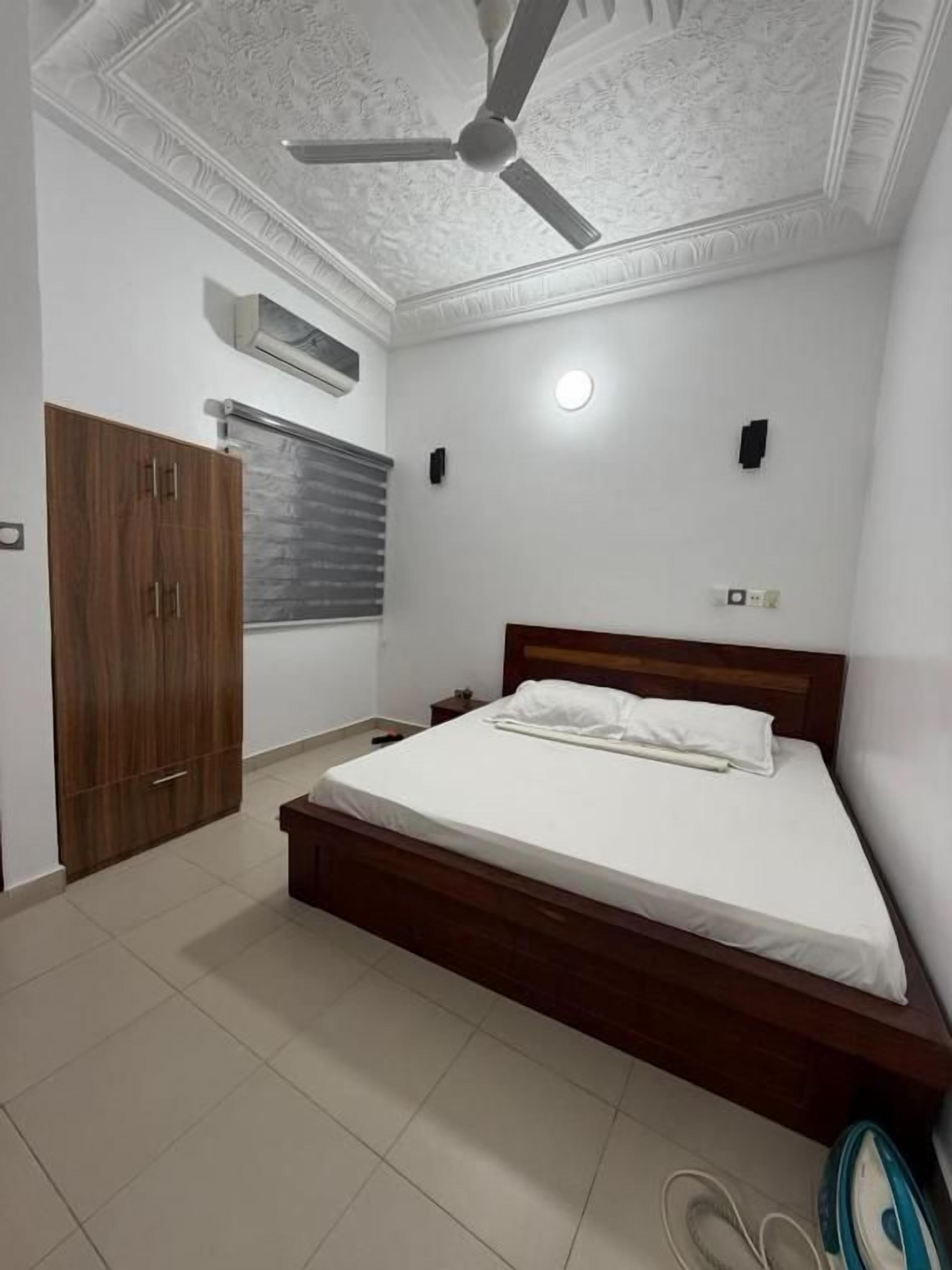 Un dormitorio con cama, armario, ventilador de techo y aire acondicionado mural.