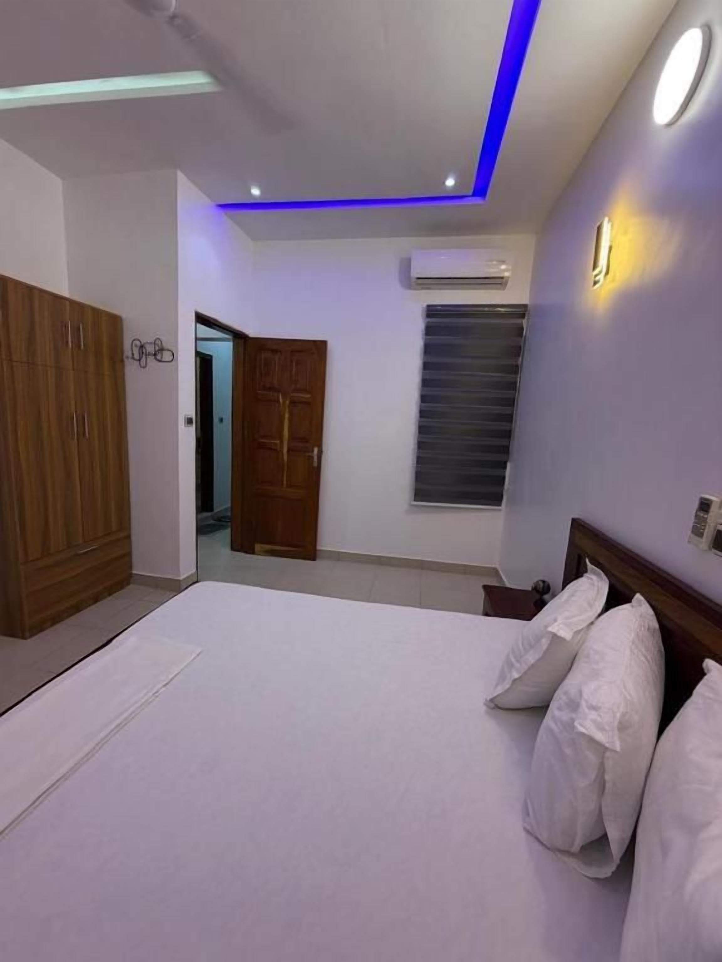 A bedroom with a bed, a wardrobe, a door, and a window.