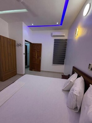 A bedroom with a bed, a wardrobe, a door, and a window.