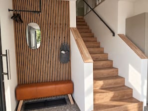 Eine Treppe mit Holzboden und Geländer, eine Bank mit Ledersitz und ein wandmontierter Spiegel.