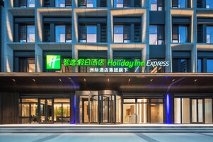 Un hotel Holiday Inn Express con una fachada moderna, ventanas amplias y una entrada destacada con puerta giratoria.