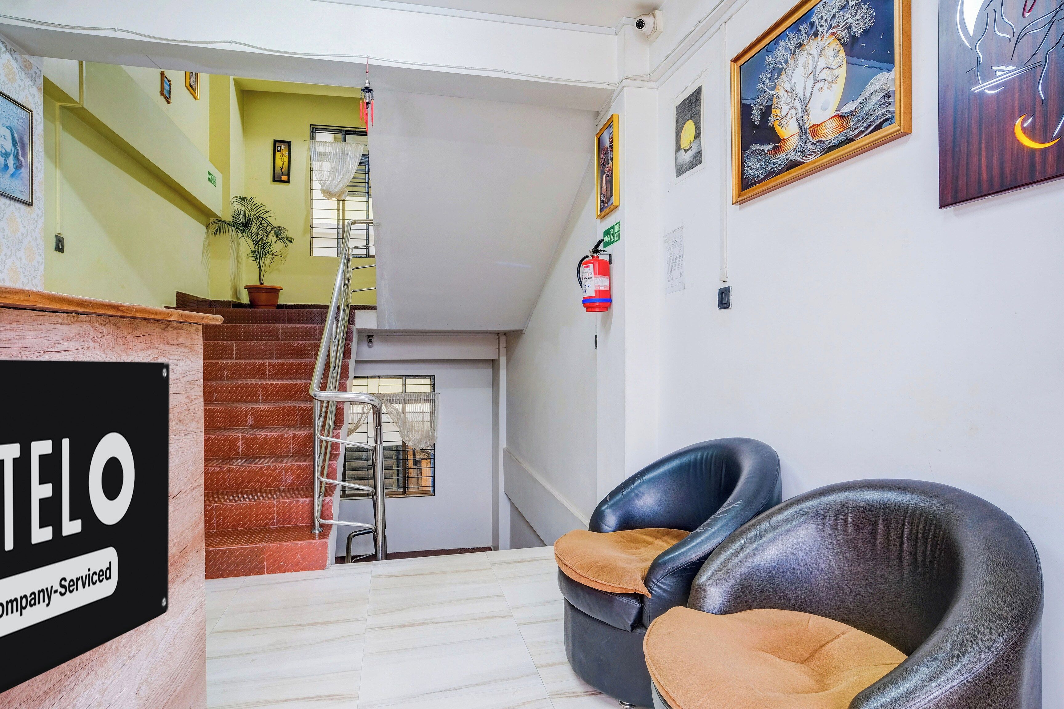 Un hall d’hôtel avec un escalier, un comptoir d’accueil et un extincteur.