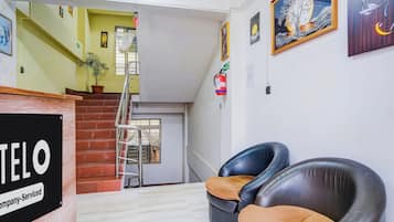 Un hall d’hôtel avec un escalier, un comptoir d’accueil et un extincteur.