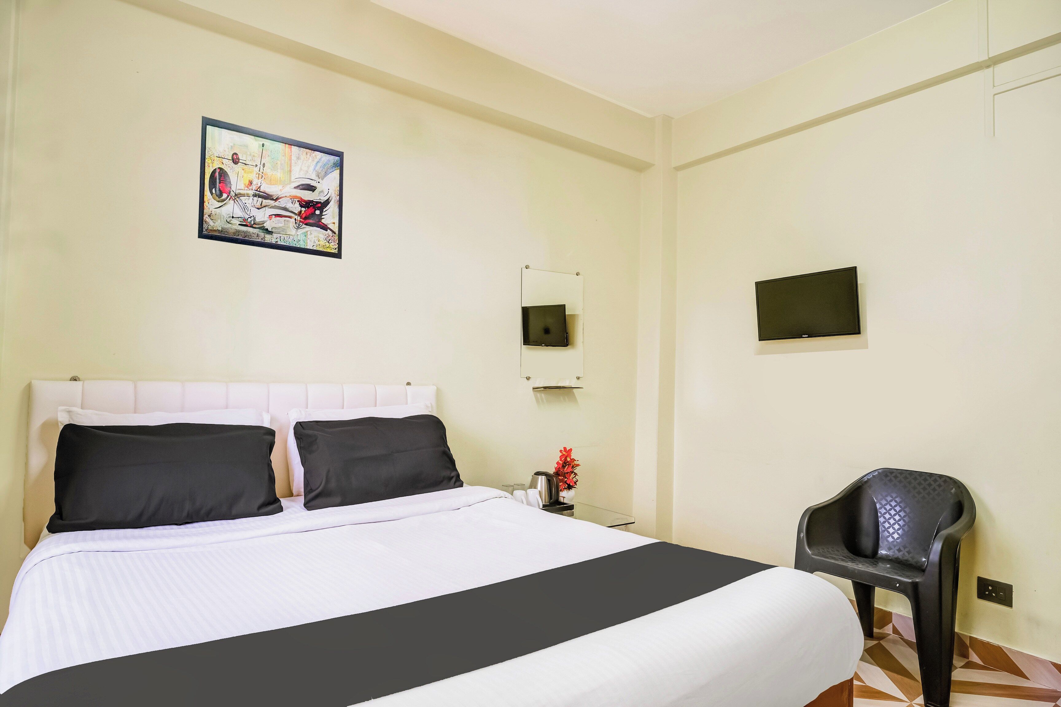 Une chambre d’hôtel avec un lit, une chaise, un tableau, un miroir et un téléviseur.