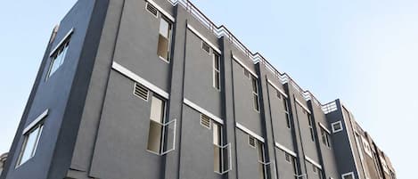 A multi-story building with a modern architectural design, featuring a series of windows and a visible storefront at the ground level.