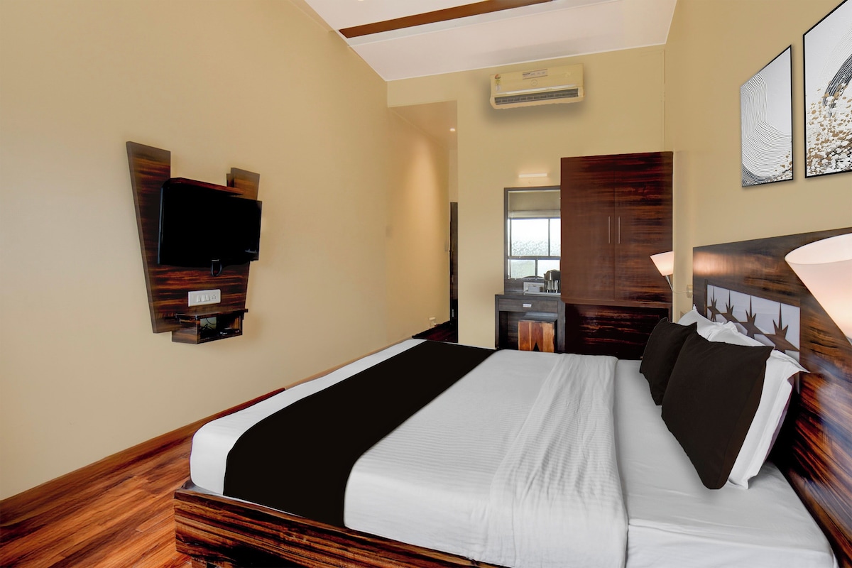 Una habitación de hotel con una cama, televisor montado en la pared, armario y espejo.