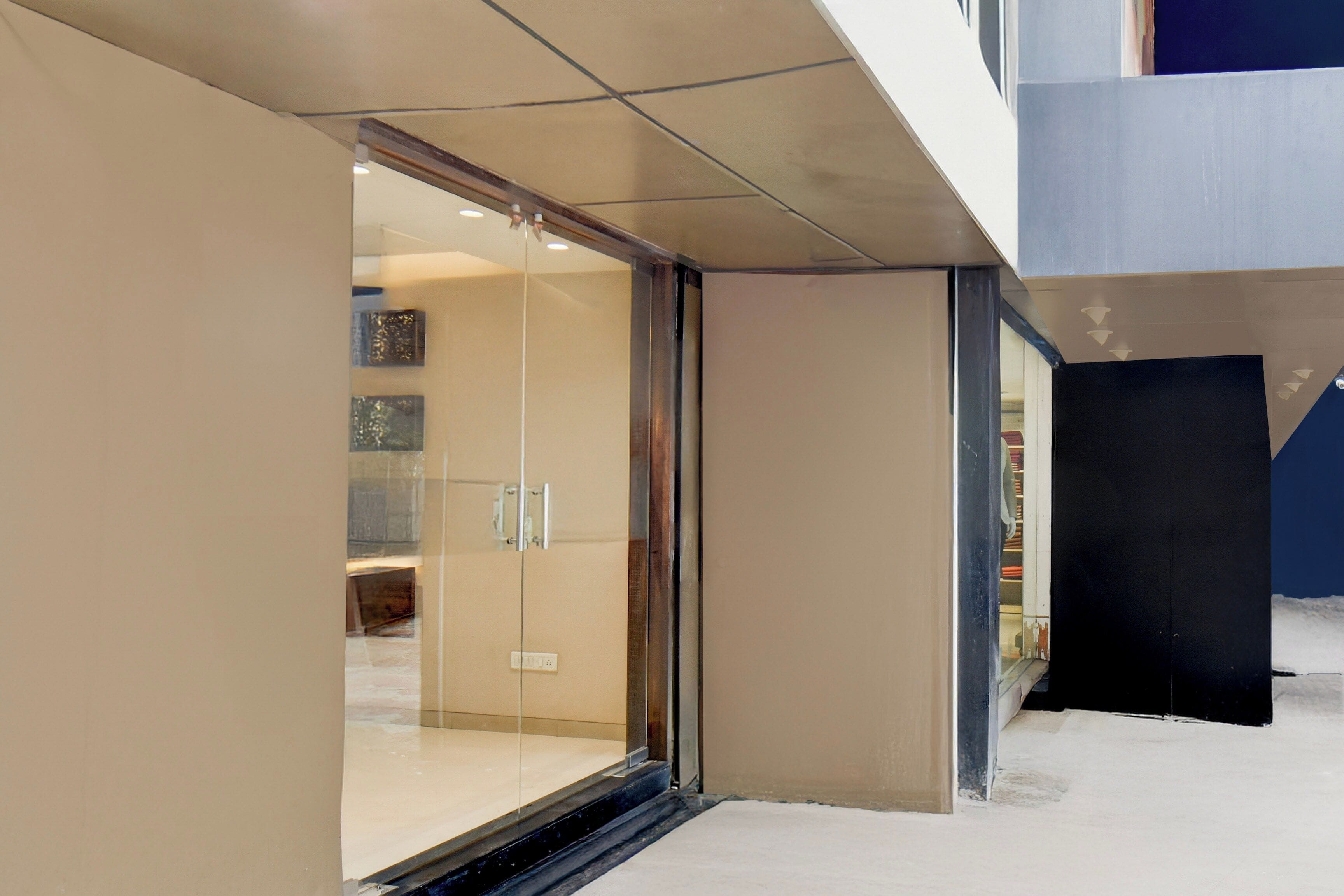 A modern interior with a glass door entrance leading to a room with a tiled floor and a visible electrical outlet.