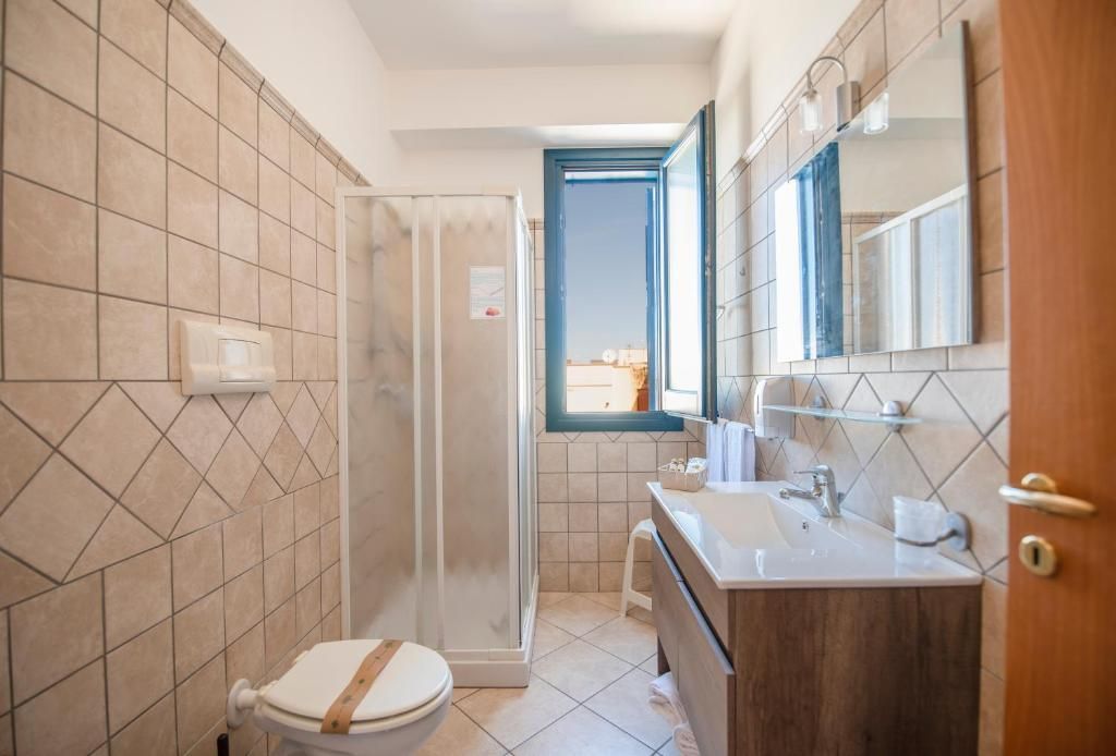 A bathroom with a toilet, shower, and sink.