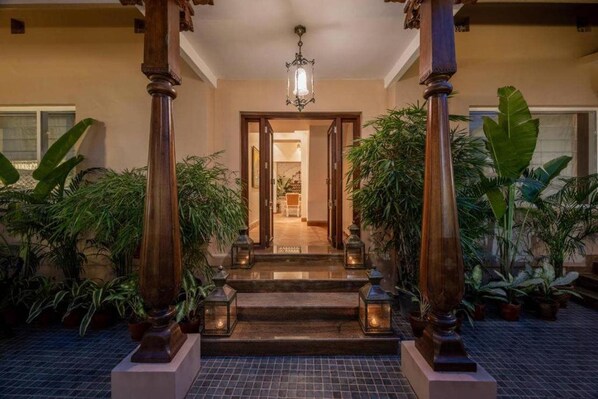 A hotel entrance with a wooden staircase, potted plants, and a chandelier. - Justa Luxe Kashi Parampara, Varanasi (Varanasi)