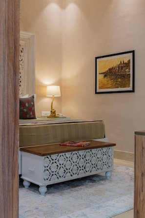 A room with a bed, a bedside table with a lamp, a framed picture on the wall, and a patterned rug. - Justa Luxe Kashi Parampara, Varanasi (Varanasi)