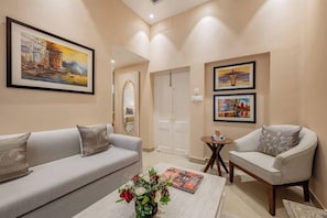 A modern living room with a sofa, armchair, and a coffee table with a floral arrangement. - Justa Luxe Kashi Parampara, Varanasi (Varanasi)