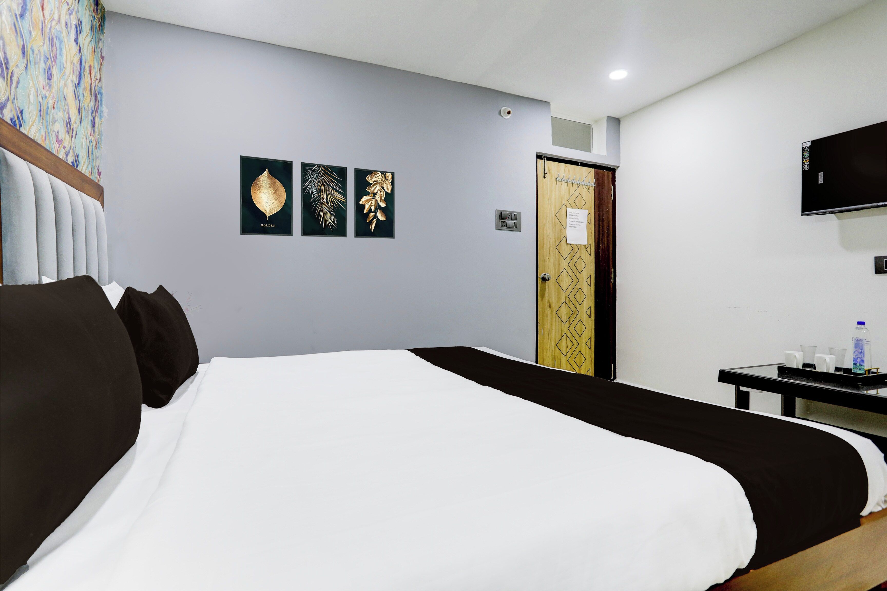 Una habitación de hotel con una cama, un televisor y obras de arte en la pared.
