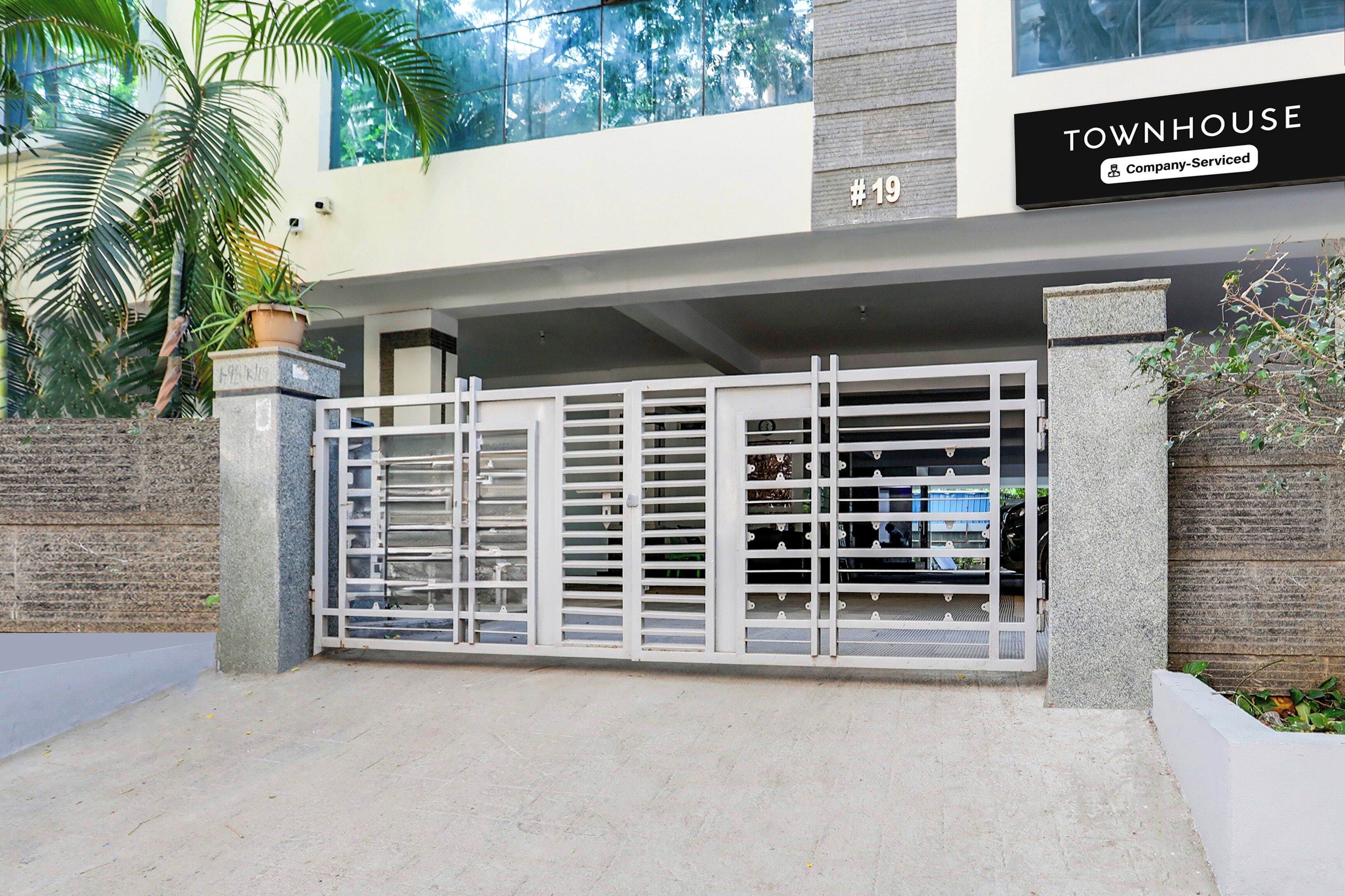 Una entrada cerrada a una propiedad con un cartel que dice 'TOWNHOUSE Company-Serviced' y el número '#19'.
