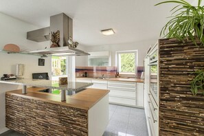 A modern kitchen with a central island, white cabinetry, and a view of greenery outside. - Holiday apartment with 1 bedroom (Gaienhofen)