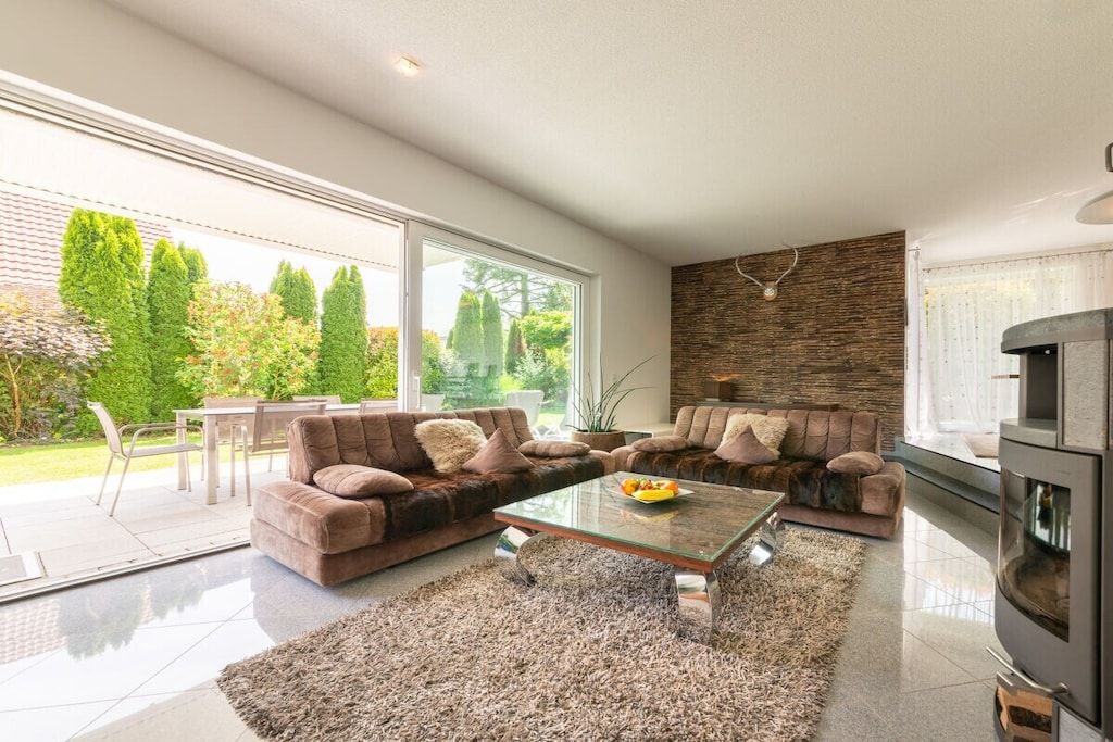 A modern living room with a glass coffee table, sofas, and a fireplace.