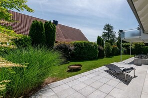 A patio with a lounge chair, a fire pit, and a well-maintained lawn. - Holiday apartment with 1 bedroom (Gaienhofen)