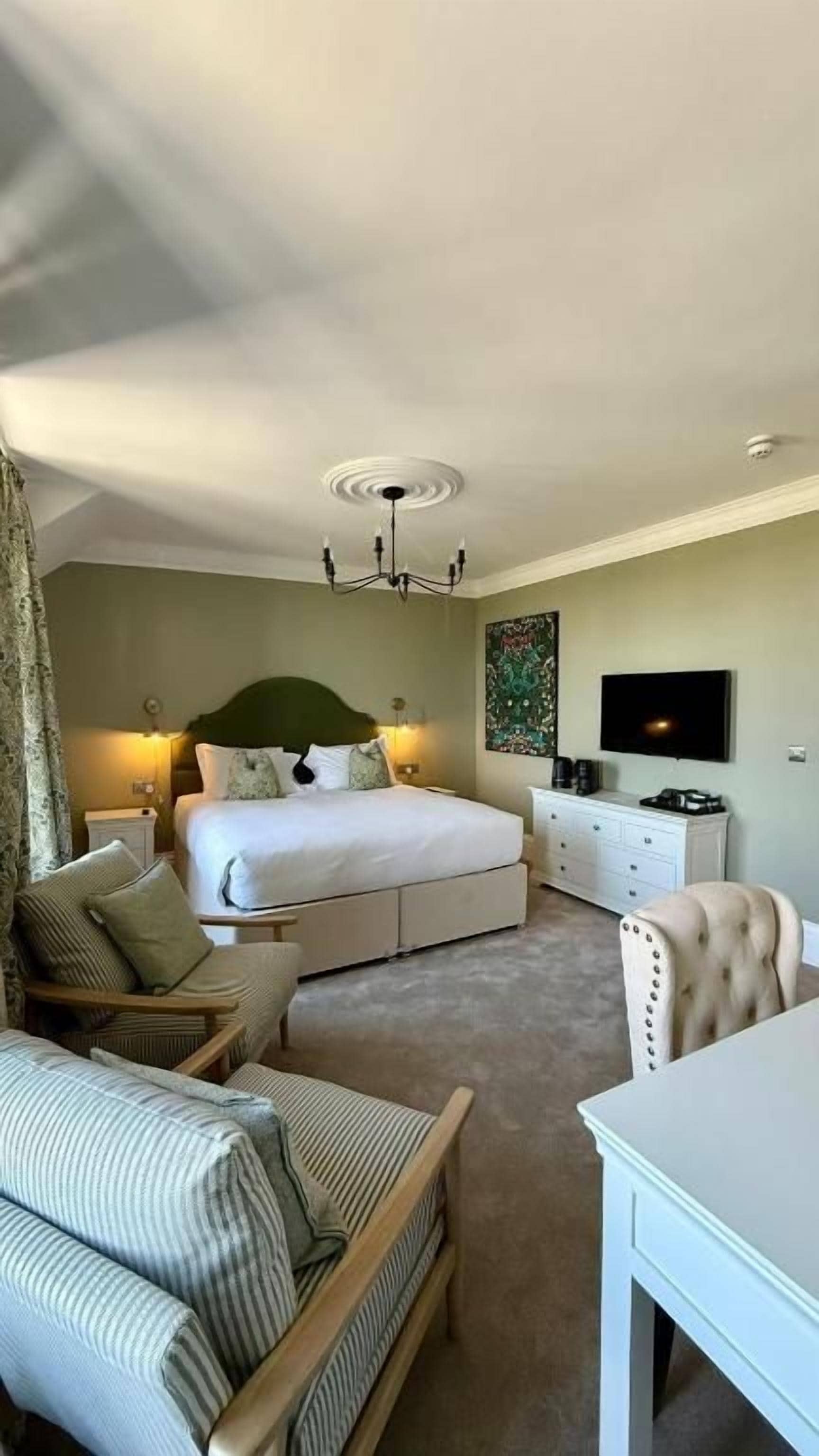 Quarto com cama grande, televisão, escrivaninha e cadeira.