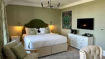 Quarto com cama grande, televisão, escrivaninha e cadeira.