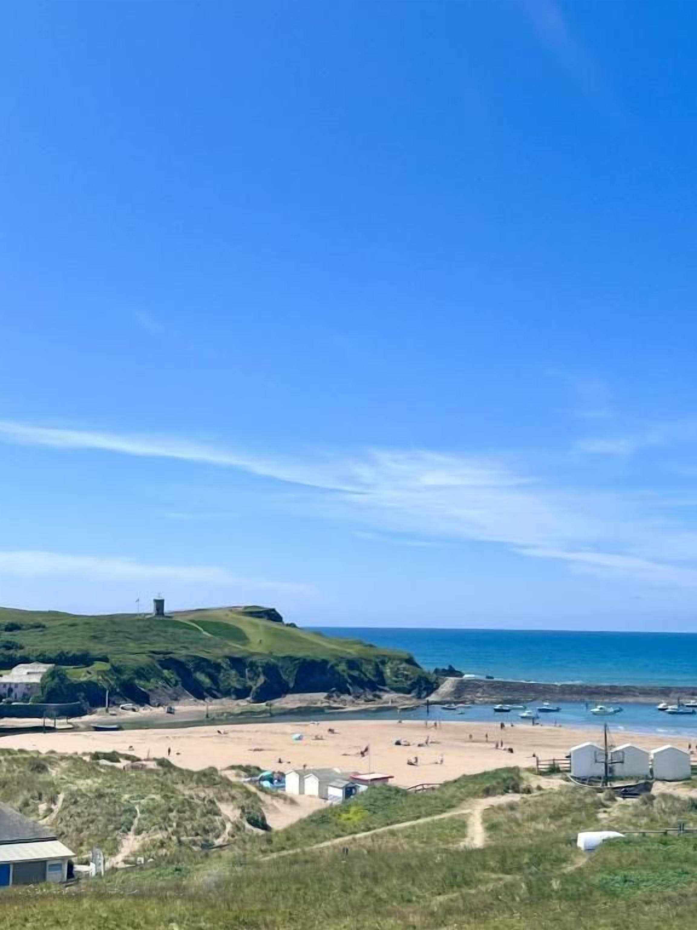 Eine Küstenlandschaft mit Strand, Leuchtturm und blauem Himmel.