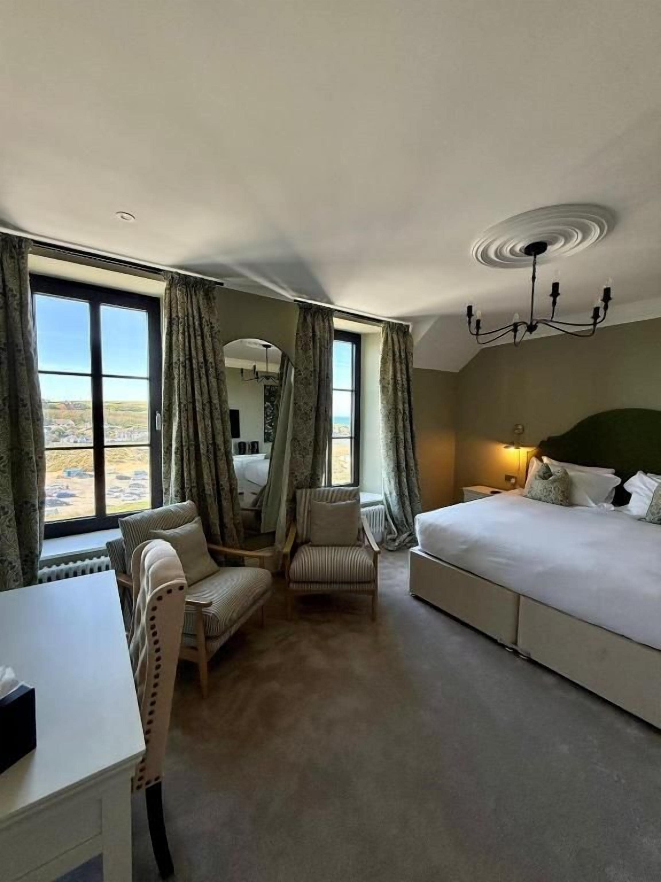 Ein Hotelzimmer mit einem Bett, zwei Stühlen, einem Schreibtisch und Blick ins Freie.