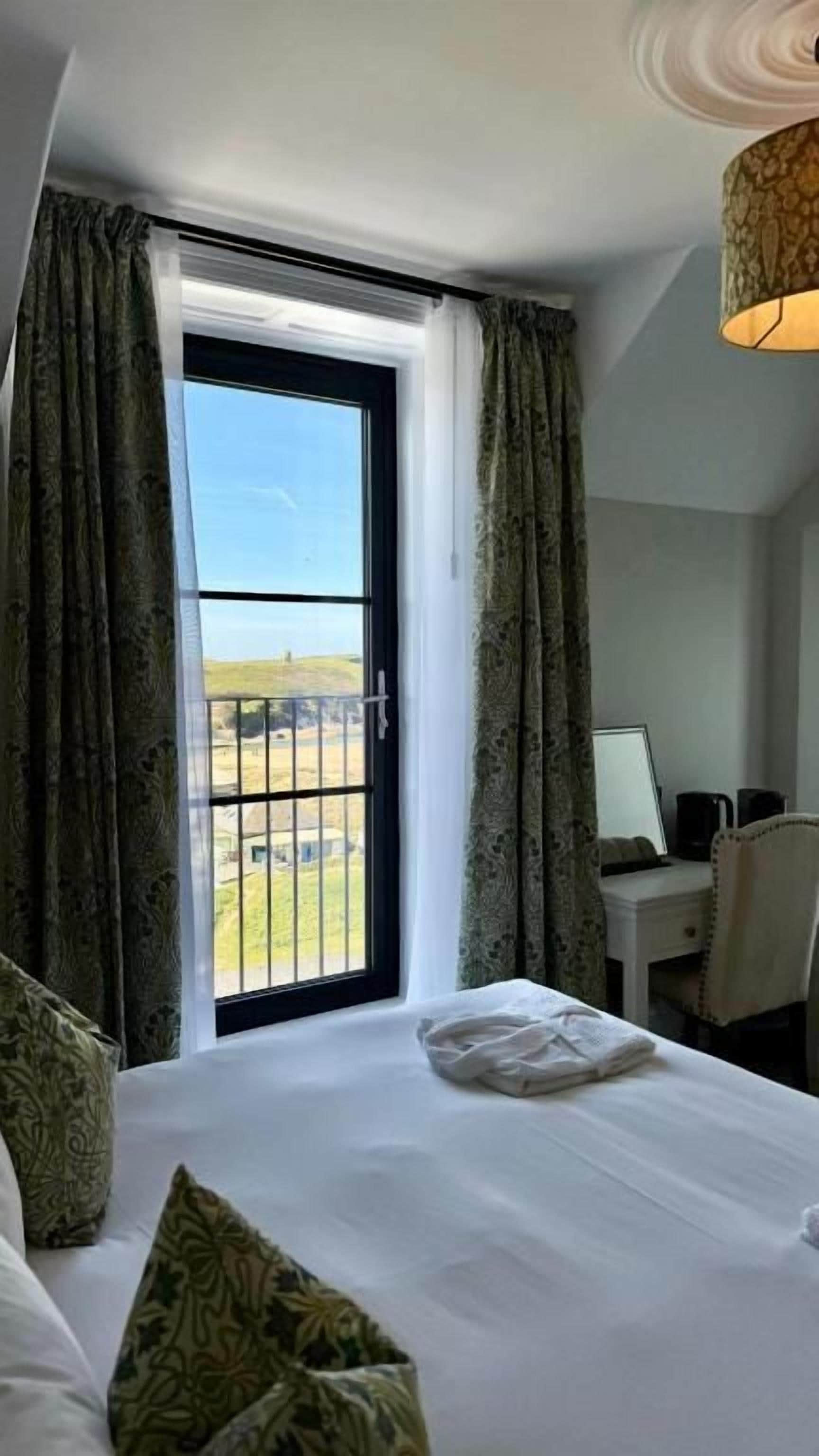 A hotel room with a bed, a desk, and a view of the outdoors.