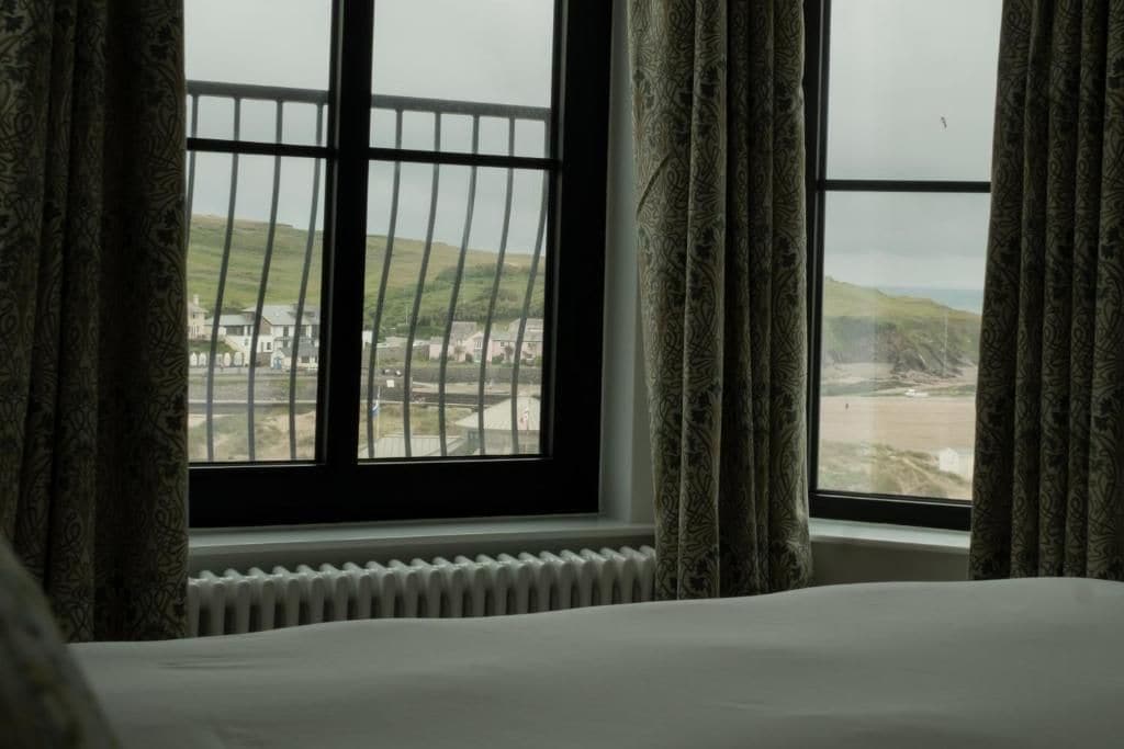 Ein Schlafzimmer mit großem Fenster mit Blick auf Strand und Gebäude.