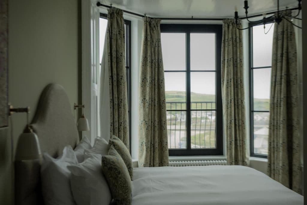 A bedroom with a large window, a bed with pillows, and a radiator.
