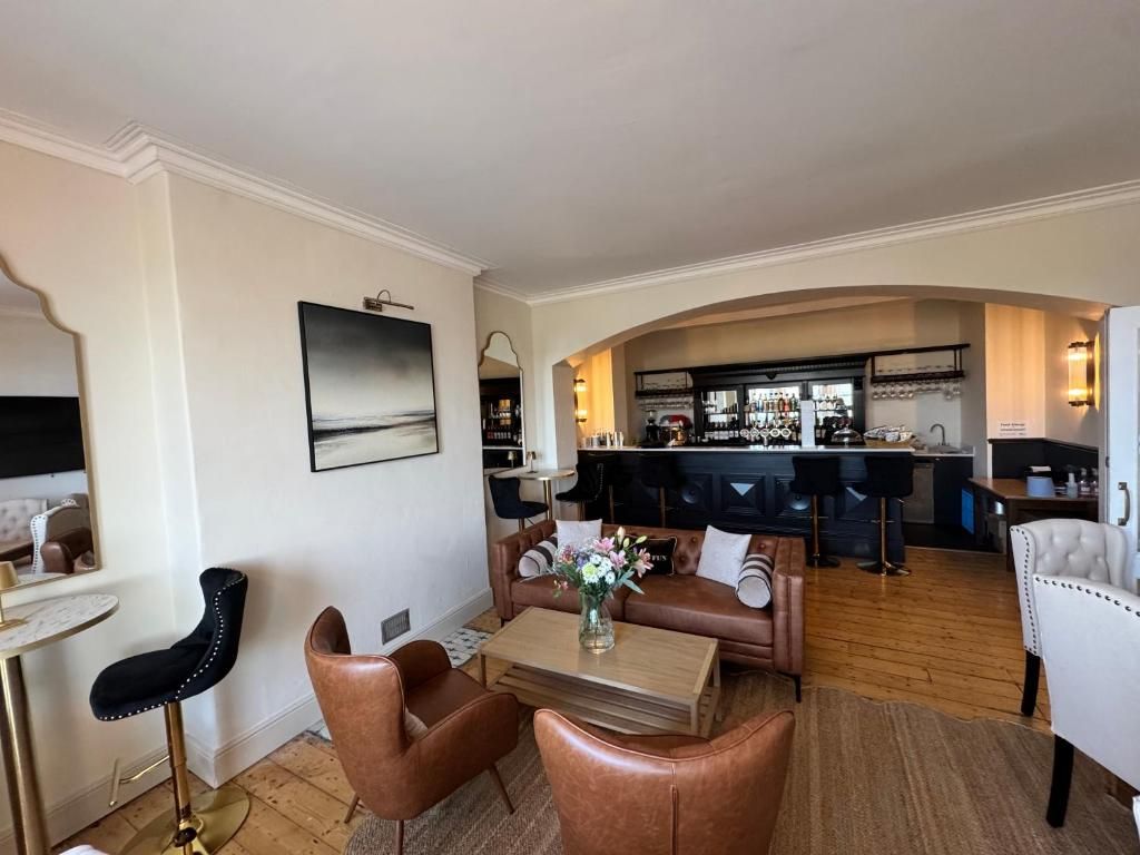 A modern living room with a sofa, coffee table, and a bar area in the background.