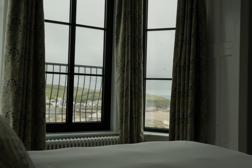 A room with a large window, curtains, and a view of a landscape.