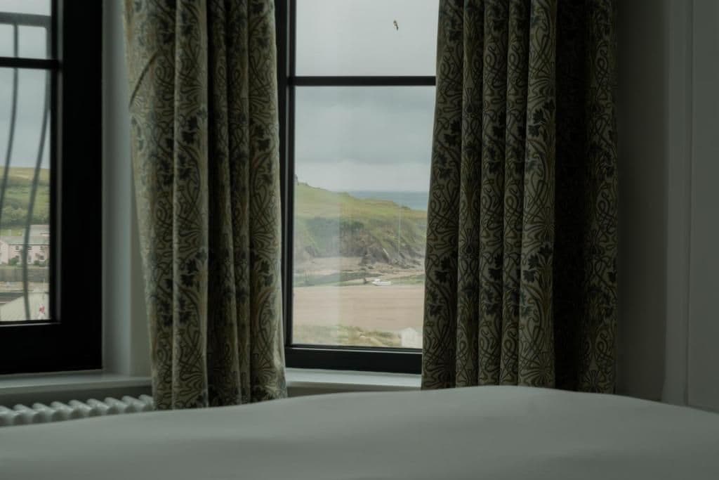 Una habitación con cama, ventana con cortinas y vista al paisaje.