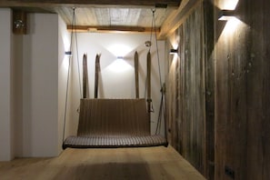 A wooden room with a hanging swing seat and wooden beams on the ceiling. - Heimat1883 - Raftsman's Daughter (Garmisch-Partenkirchen)