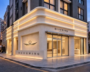 A modern building with a sign reading 'BLUEWING YACHT HOTEL' and a logo with wings. - BLUEWING YACHT HOTEL (BUSAN)