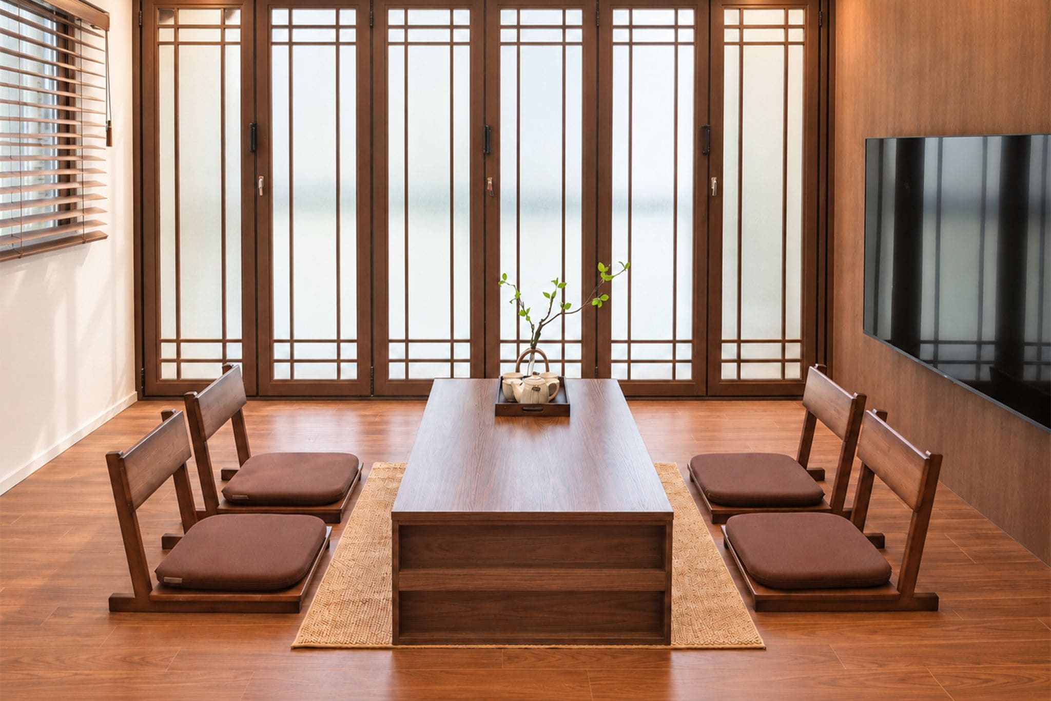 A modern dining room with a wooden table, cushioned chairs, and a view through shoji screens.