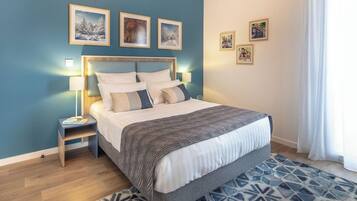Quarto com cama, abajures, tapete estampado e quadros nas paredes.