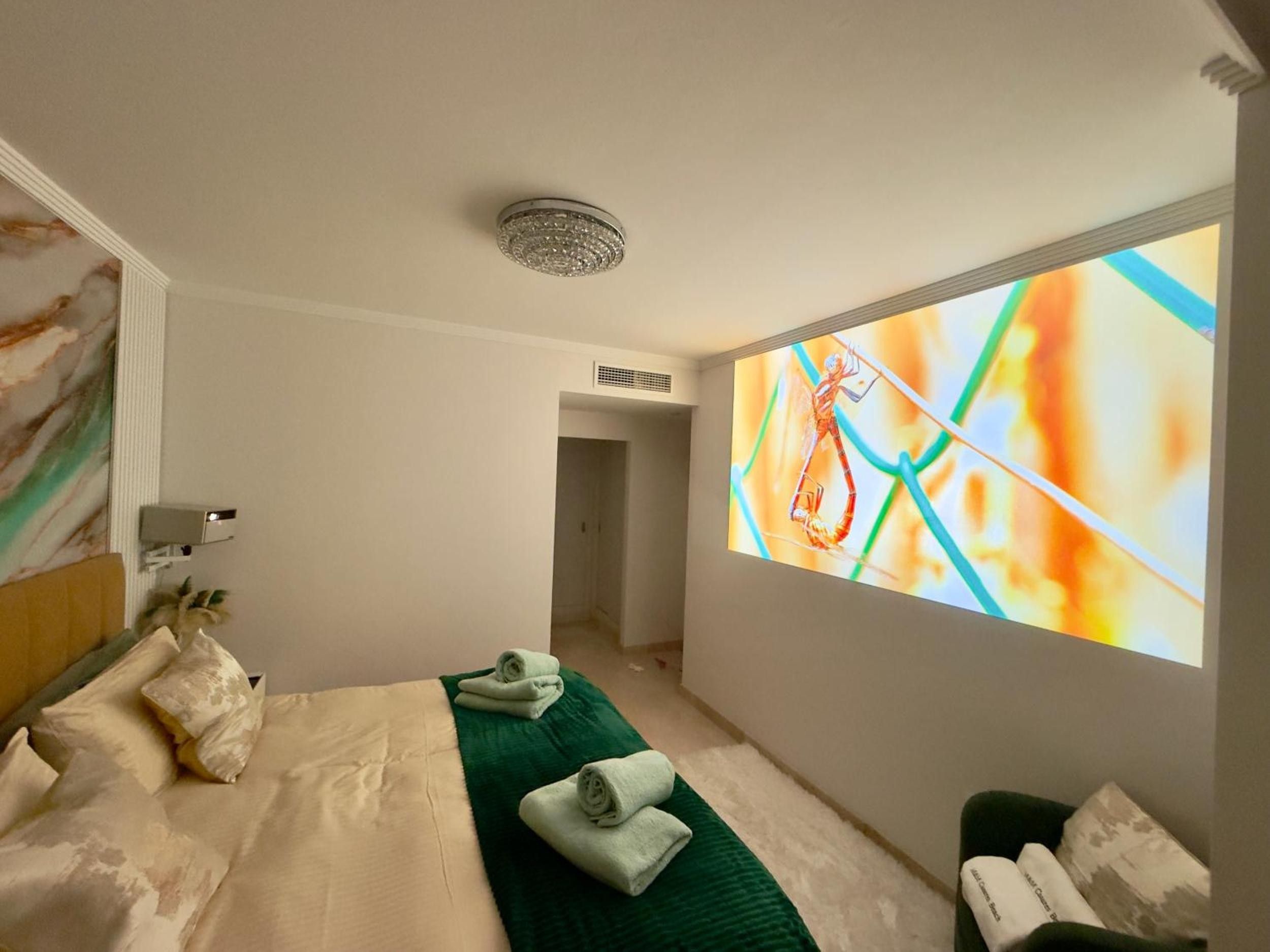 Ein Hotelzimmer mit einem Bett, einem grünen Teppich und einem an der Wand befestigten Fernseher, der ein farbenfrohes Bild zeigt.