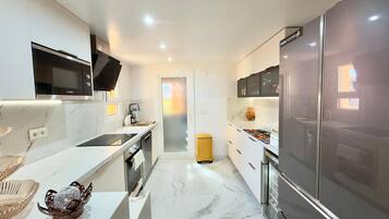 Een moderne keuken met een Bosch magnetron, een grote koelkast en een gele prullenbak.