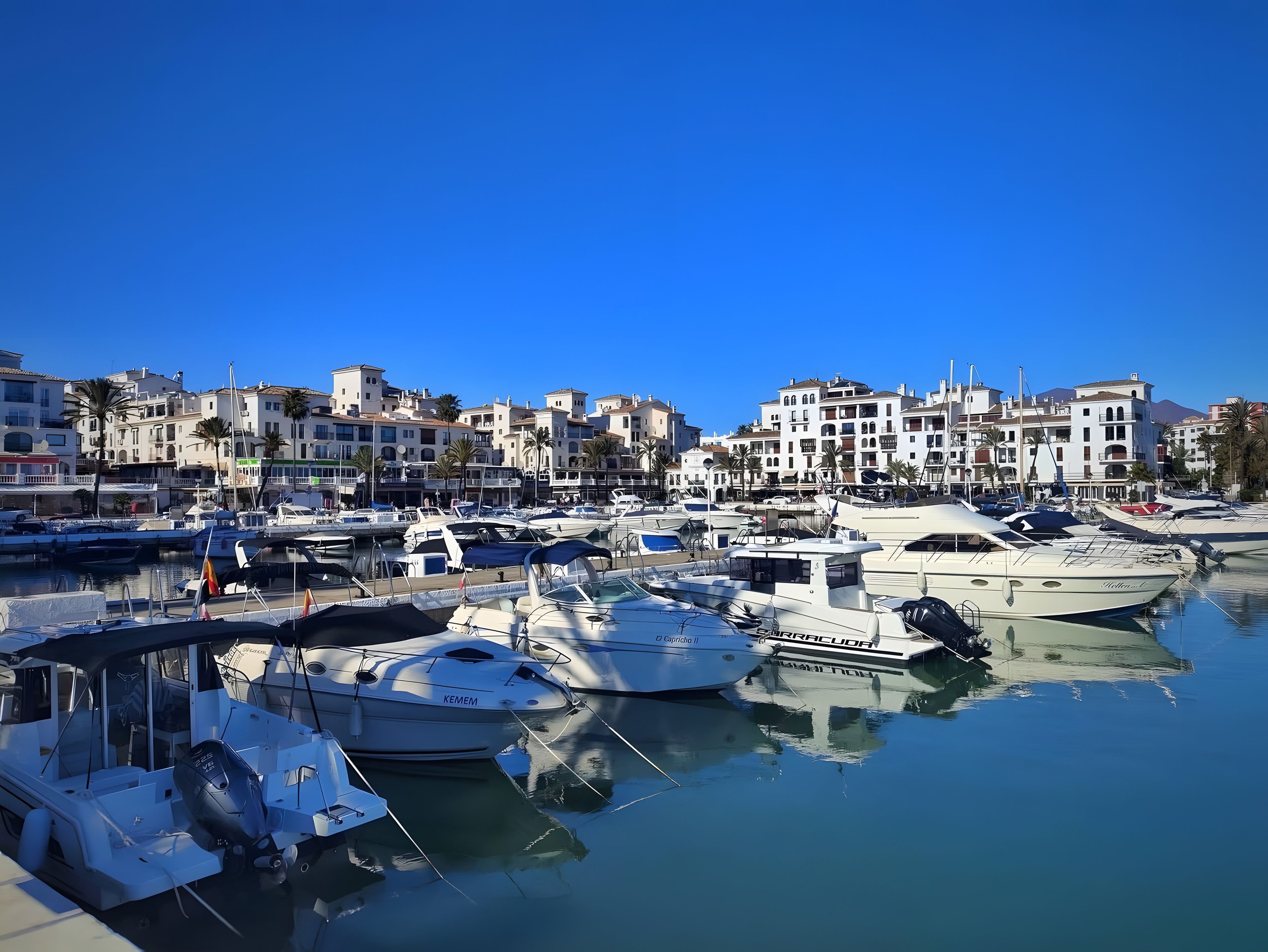 Un port de plaisance où sont amarrés de nombreux bateaux, entouré d’immeubles à plusieurs étages.