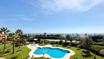 Un complexe hôtelier doté d’une grande piscine, de palmiers et offrant une vue sur la mer.