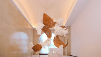 Un interior moderno con una silla blanca, una escultura de madera y un diseño minimalista.