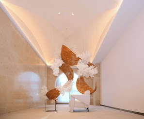 Un interior moderno con una silla blanca, una escultura de madera y un diseño minimalista.