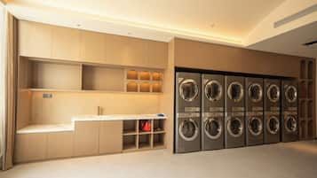 A laundry facility with multiple washing machines and a bench.