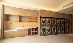 Un cuarto de lavandería con varias lavadoras y un banco.