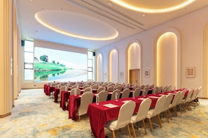 A conference room with a long table, chairs, and a large screen displaying a scenic view.