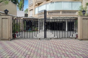 Una entrada protegida por un portón metálico y un camino de entrada pavimentado que conduce a un edificio.