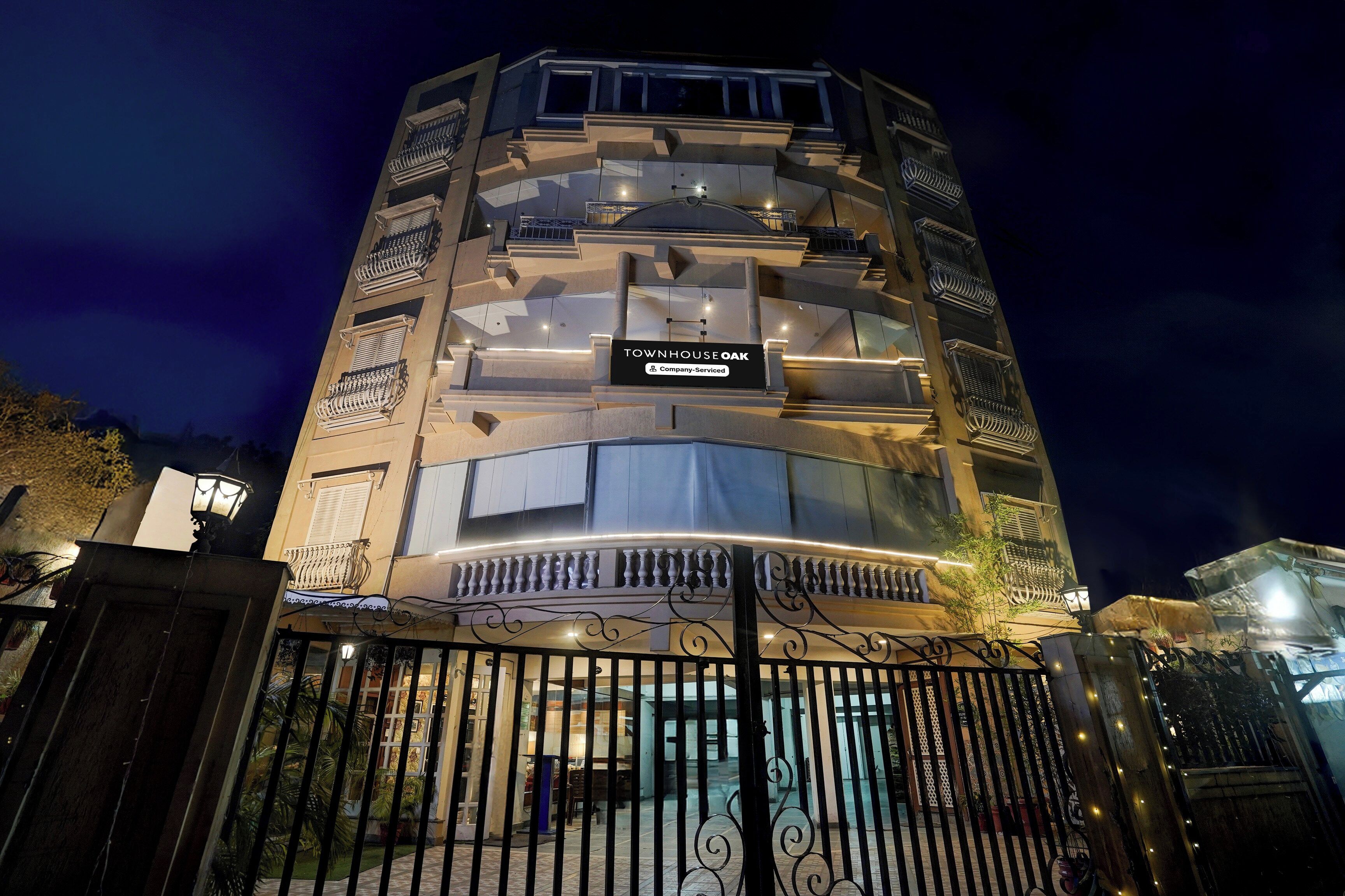 Um edifício de vários andares com uma placa indicando 'TOWNHOUSE OAK' e a identificação de serviço da empresa.