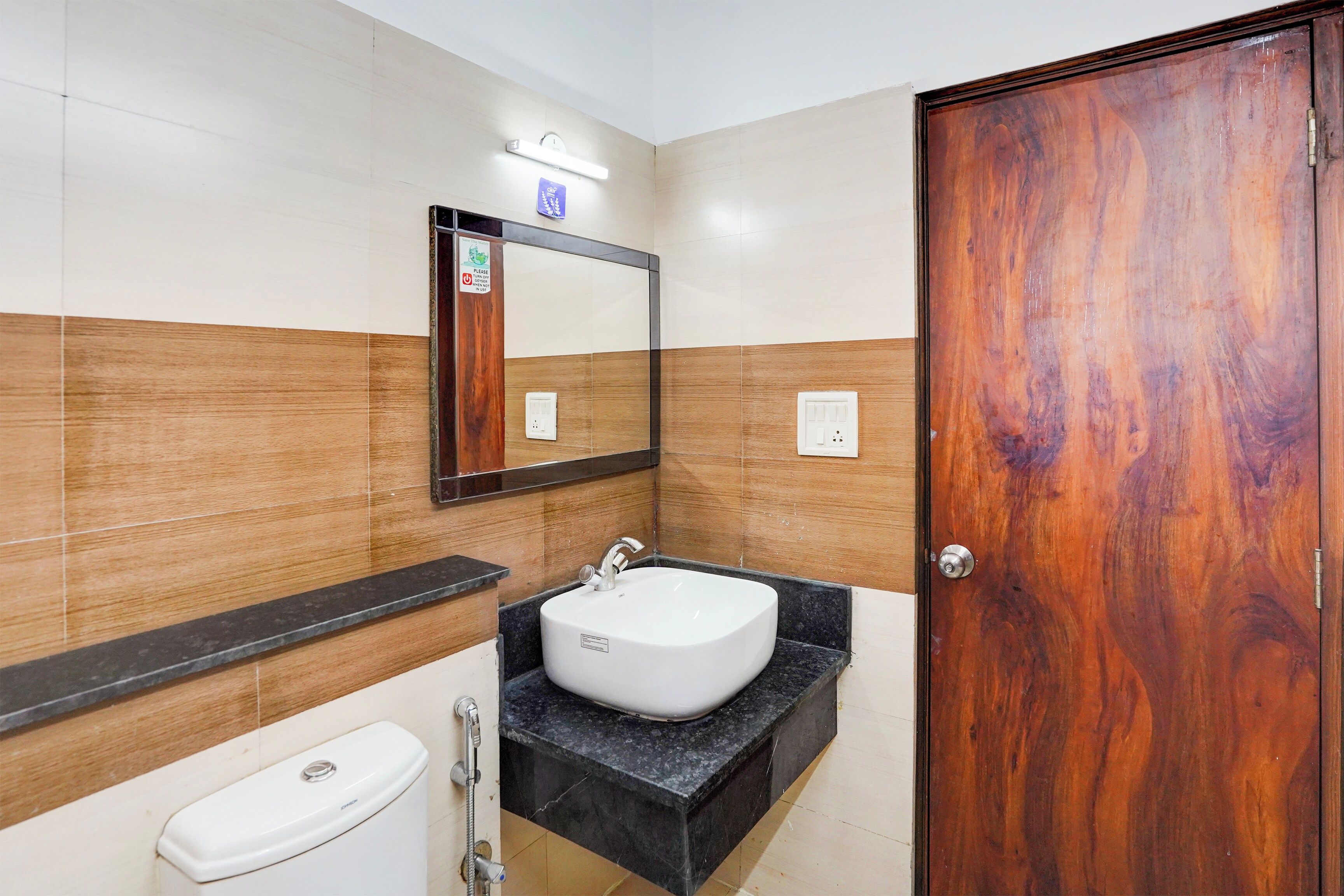 A bathroom with a white toilet, a sink with a mirror above it, and a wooden door.